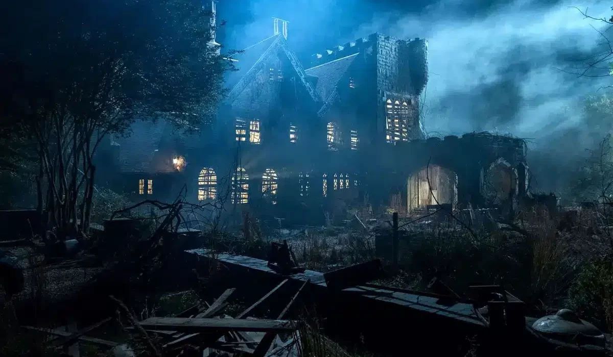 fi_TheHauntingOfHillHouse Exterior image of the haunted house at night under misty skies, with every window glowing with light from inside